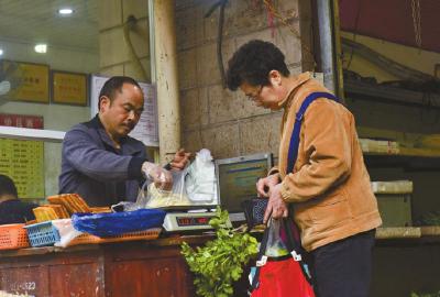 蔬菜店门口老板空时帮顾客结账.